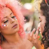 Kolorowe ozdoby i złote cienie na twarzy, idealny makijaż na festiwal.