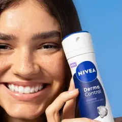 Uśmiechnięta kobieta trzyma NIVEA Derma Control, idealny produkt na swędzenie pod pachami.