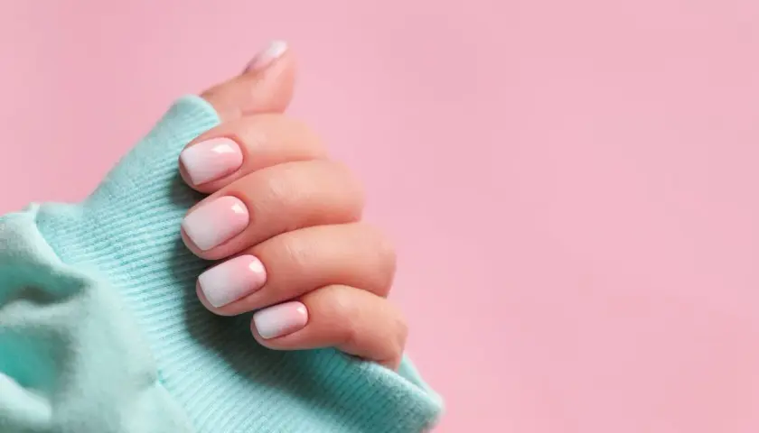 Dłoń z paznokciami w stylu baby boomer, delikatny gradient różu i bieli. Idealny sposób, jak zrobić baby boomer na paznokciach.