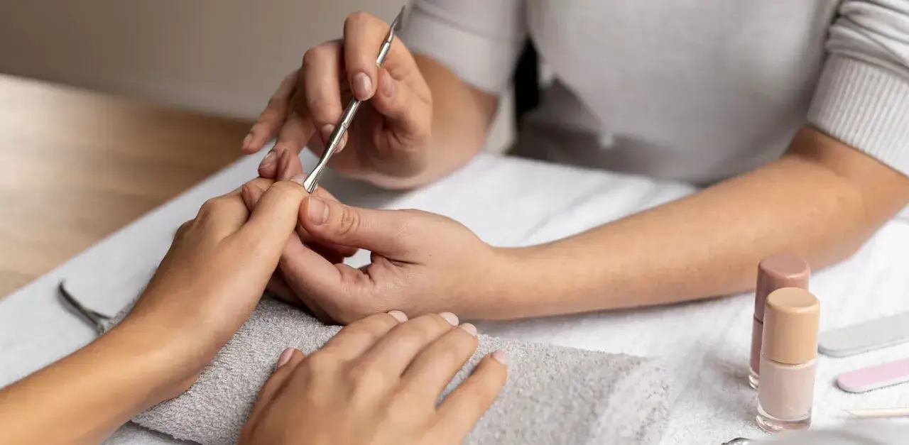 Profesjonalny manicure: jak usunąć sk&oacute;rki wok&oacute;ł paznokci. Narzędzia i lakiery do paznokci na stole.